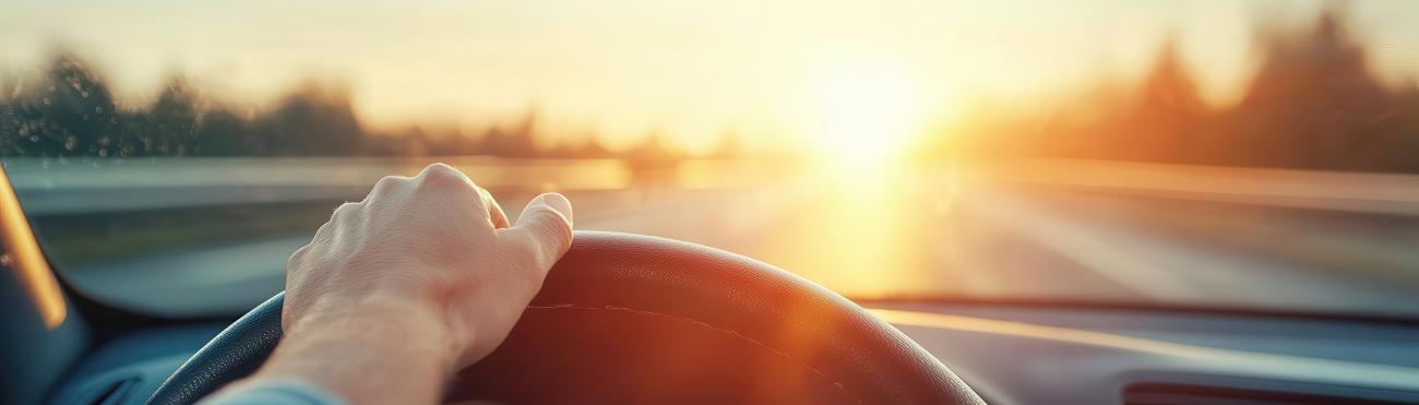 Hand on steering wheel looking into blinding sun
